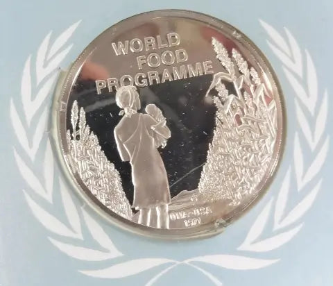 This is a 1971 UNA-USA Sterling Commemorative Medal of World Food Programme. The image on the medal is of a woman holding a child. Standing next to wheat.